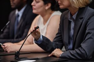 A female expert witness adjusting her microphone before giving technical testimony in court.