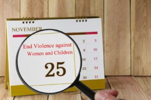Magnifying glass held over a calendar highlighting the International Day for the Elimination of Violence against Women and Children
